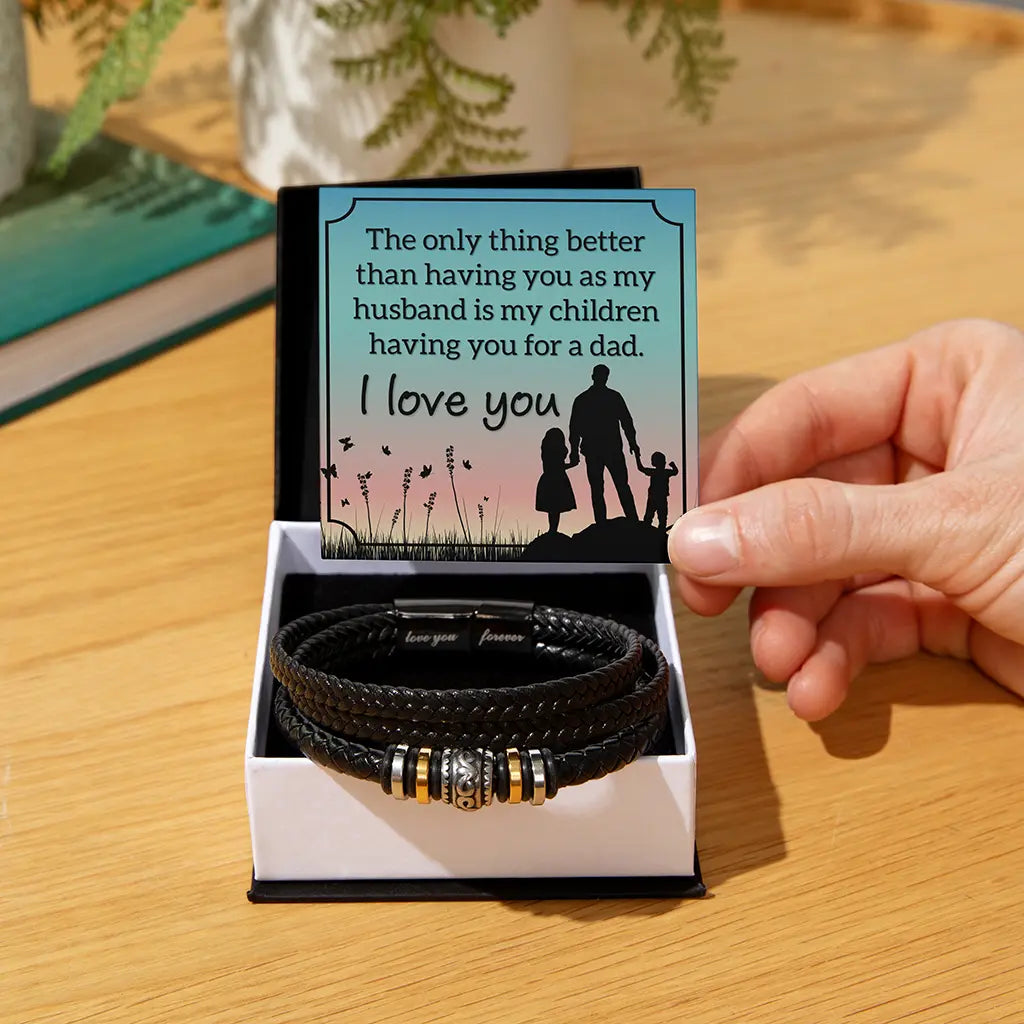 Black leather bracelet with gold accents in a box with a sentimental card on a wooden surface