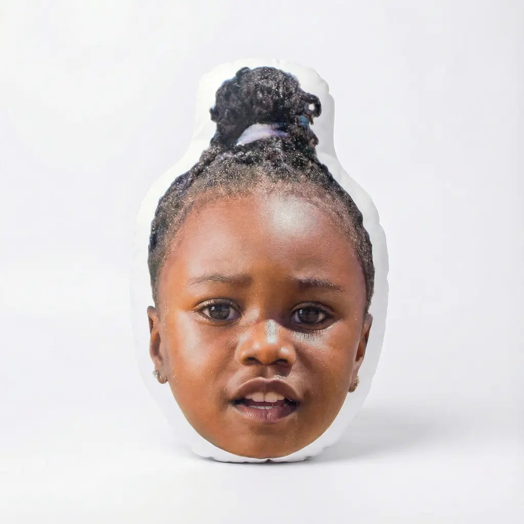 Face pillow of a young child with braided hair on a white background