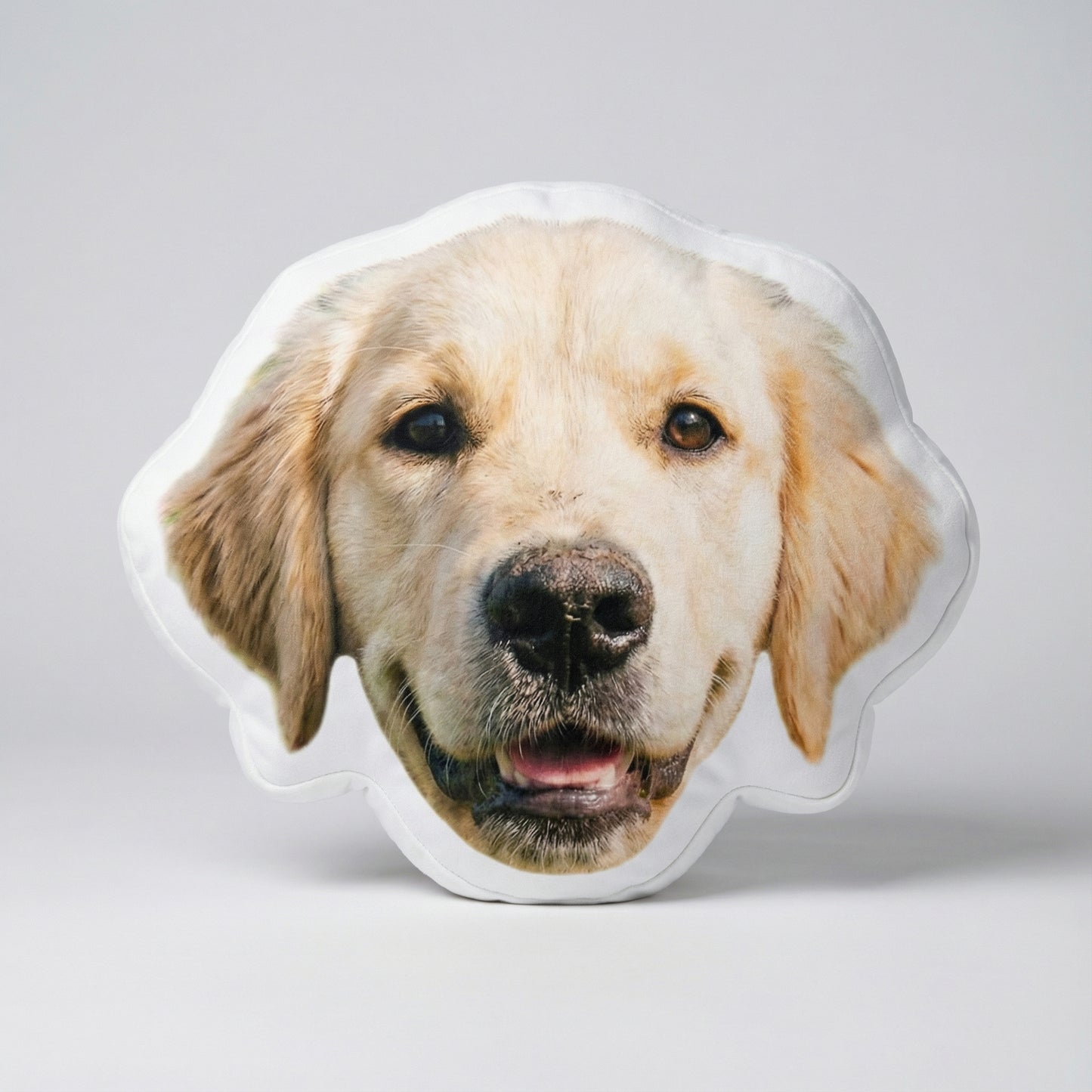 Dog-shaped pillow with a golden retriever face on a light gray background